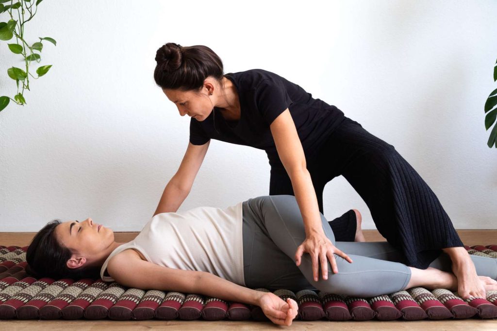 therapist performing yoga stretches on client